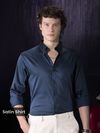 Man wearing a navy satin shirt for men with rolled-up sleeves.